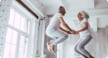 Older couple jumping up and down on bed