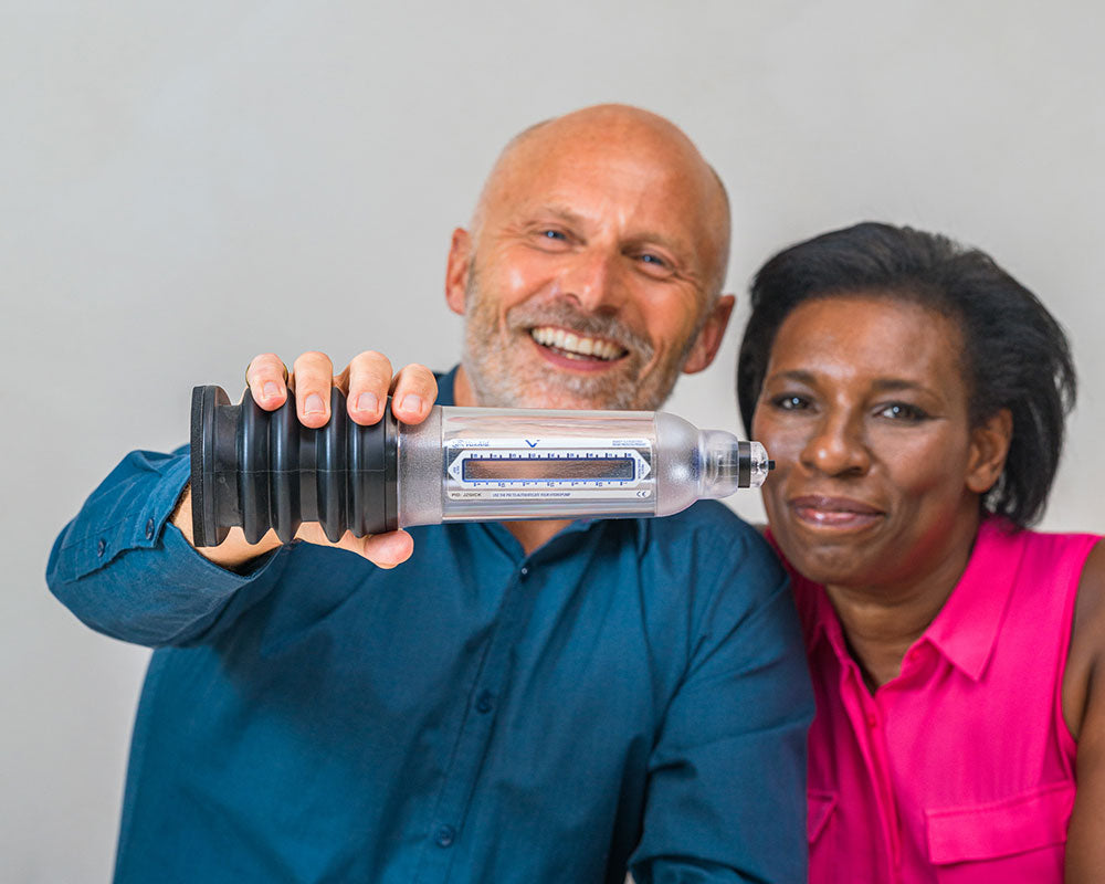 Smiling man holding up a VaxAid Penis Pump next to a smiling woman