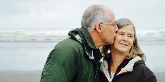 Elder man kissing woman on cheek on seaside
