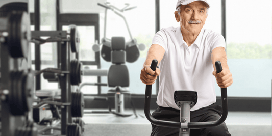 A senior man is engaged in a workout on an exercise bike in a gym, demonstrating active fitness participation.