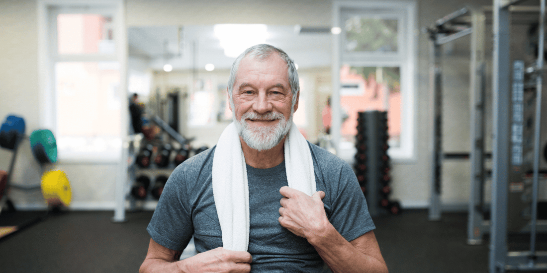 An older man with a smile holds a towel, reflecting a positive and approachable attitude.