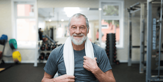 An older man with a smile holds a towel, reflecting a positive and approachable attitude.
