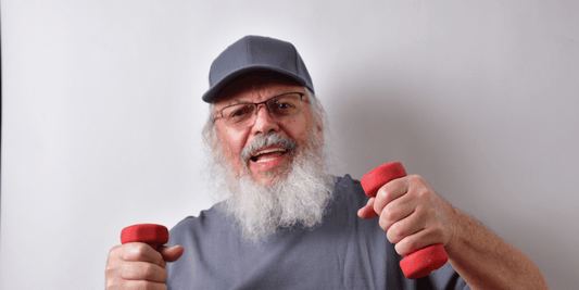 An elderly man with a beard and glasses holds two red dumbbells, showcasing strength and fitness.