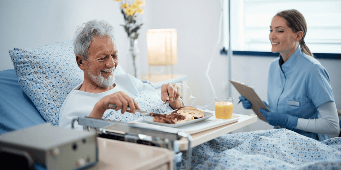 A nurse assists an elderly man with breakfast in a hospital bed, promoting care and nourishment in a medical setting.