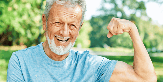  A senior man proudly displays his muscular physique by flexing, emphasizing his fitness and determination.