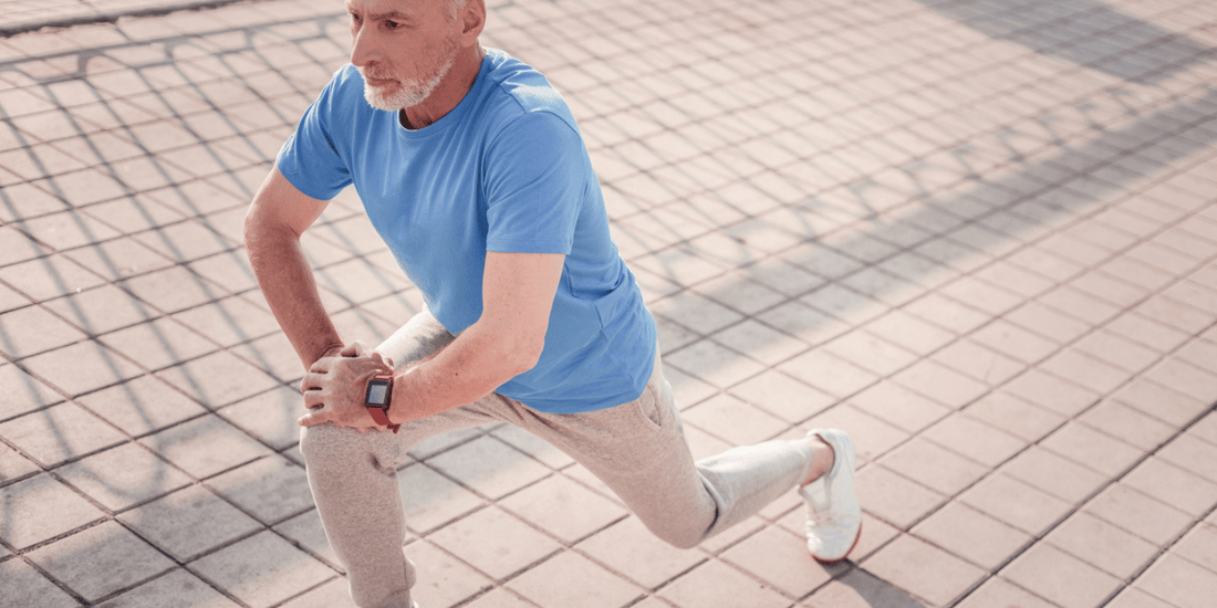 A senior man performs a stretching exercise on a street, emphasizing fitness and well-being during his run.