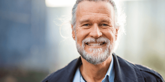 A man with a beard wearing a blue shirt, smiling and looking directly at the camera.