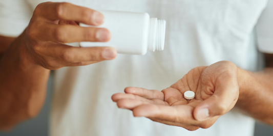 Person holding a medication tablet and bottle while considering how other medicines may affect ED treatment options.