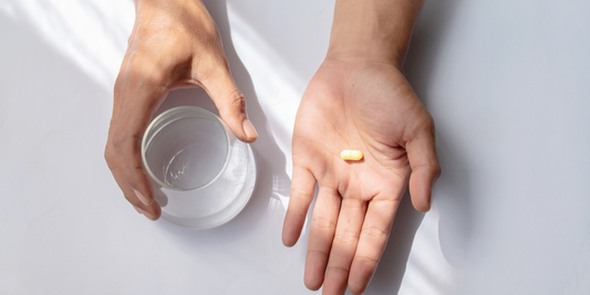 Person holding an ED tablet and a glass of water while considering treatment options.