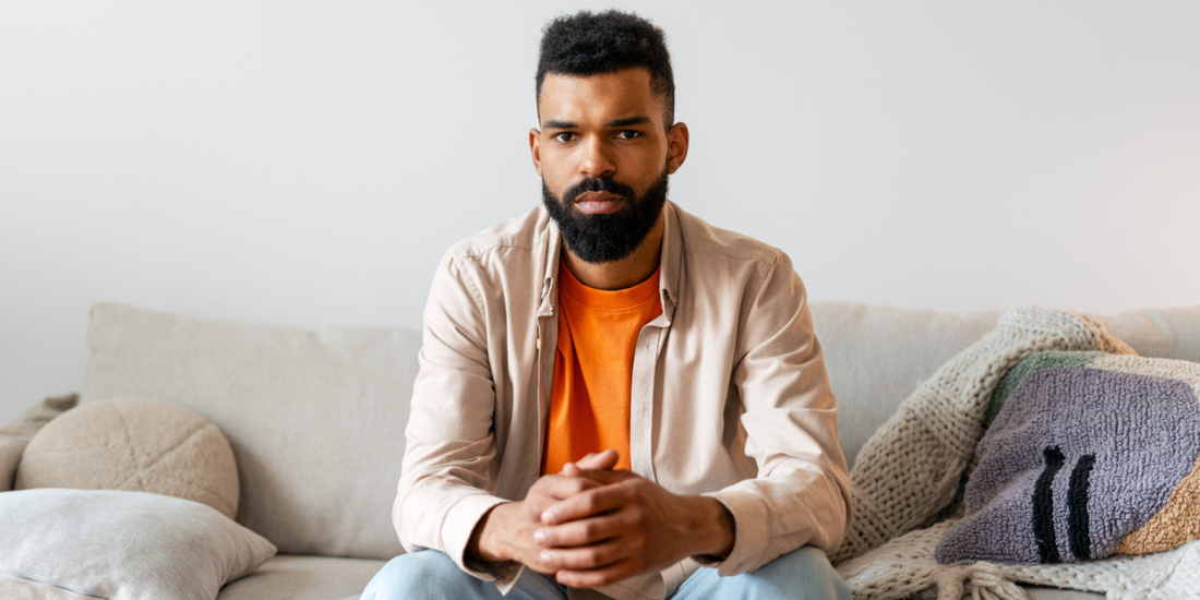 Man sitting thoughtfully on a sofa at home, reflecting on his health and wellbeing.