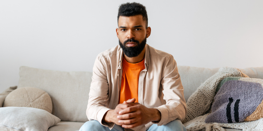 Man sitting thoughtfully on a sofa at home, reflecting on his health and wellbeing.