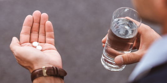 Man holding ED tablets in one hand and a glass of water in the other, representing erectile dysfunction medication and treatment review.