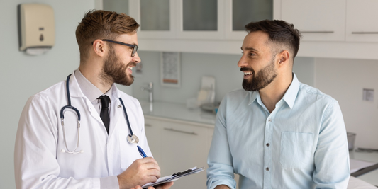 Doctor speaking with a male patient during a consultation about using a vacuum erection device and reviewing treatment progress.