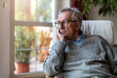 Picture of an older man looking out the window with his face on his hand