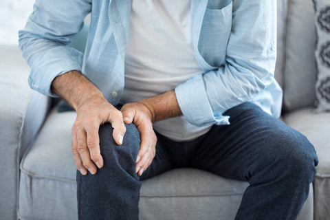 Picture of man holding knee sitting on a couch