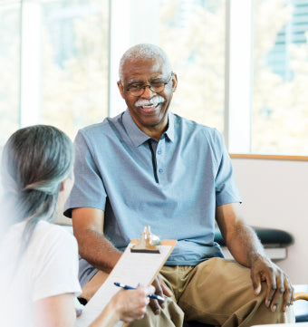 Man smiling sitting on Doctors exam table while talking with the doctor