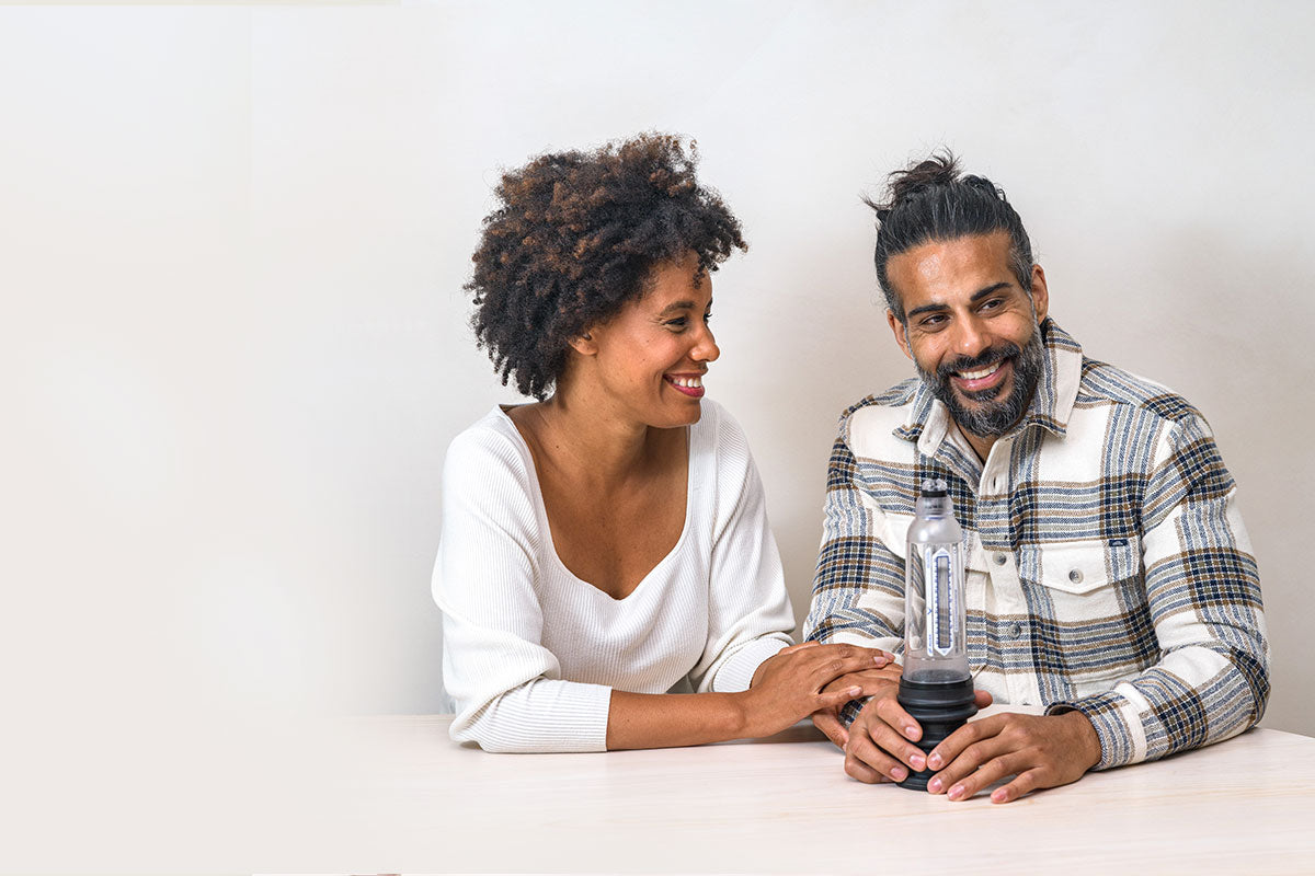 Man holding Vaxaid Penis pump on a table while wife looks at him