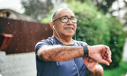 A man wearing headphones checking his pulse while outdoors